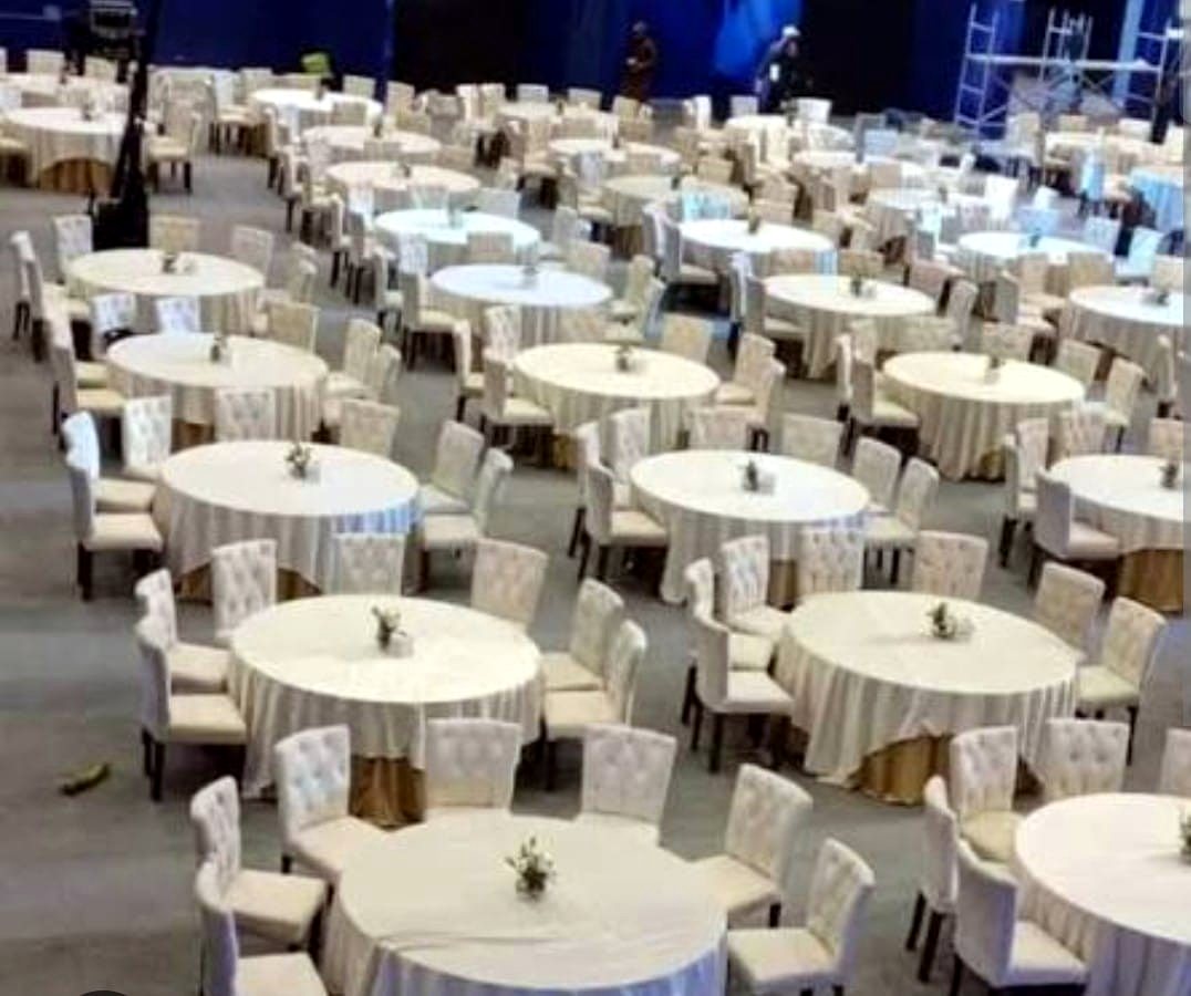 Banquet hall filled with round tables and tufted white dining chairs