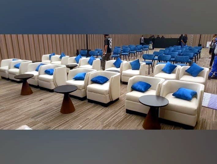 Ballroom with blue lighting and rows of grey tub chairs on swivel bases