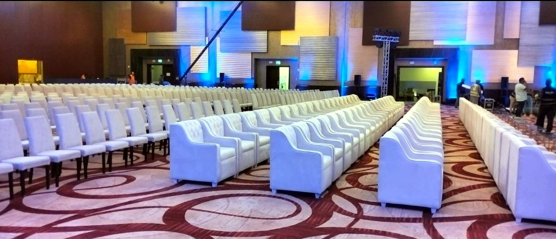 Large conference ballroom with rows of white sofas and banquet chairs