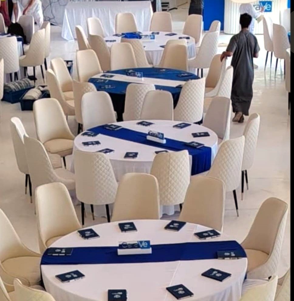 Round dining tables with white covers and quilted chairs prepared for a corporate event